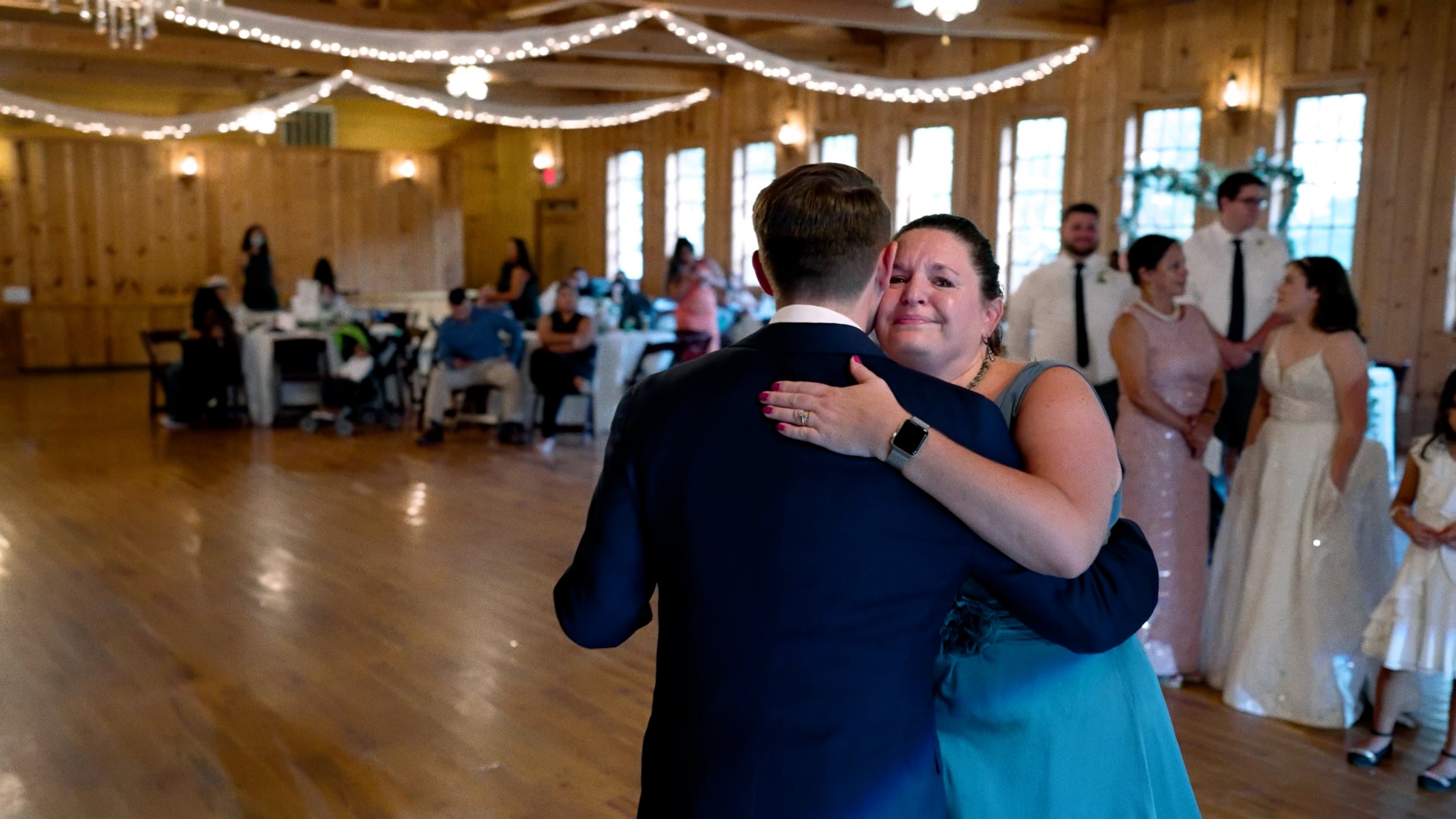 groom dances with mother during reception mom crying hug