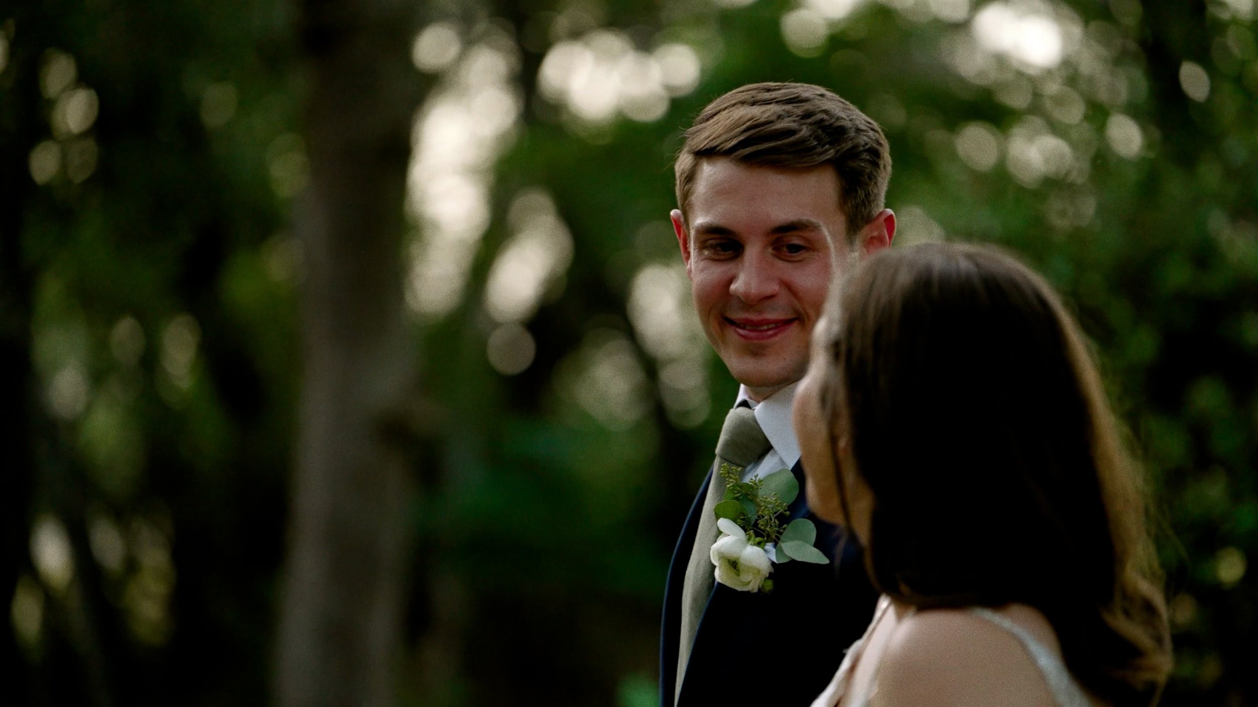 groom gazes at bride lovingly walking outside closeup bokeh