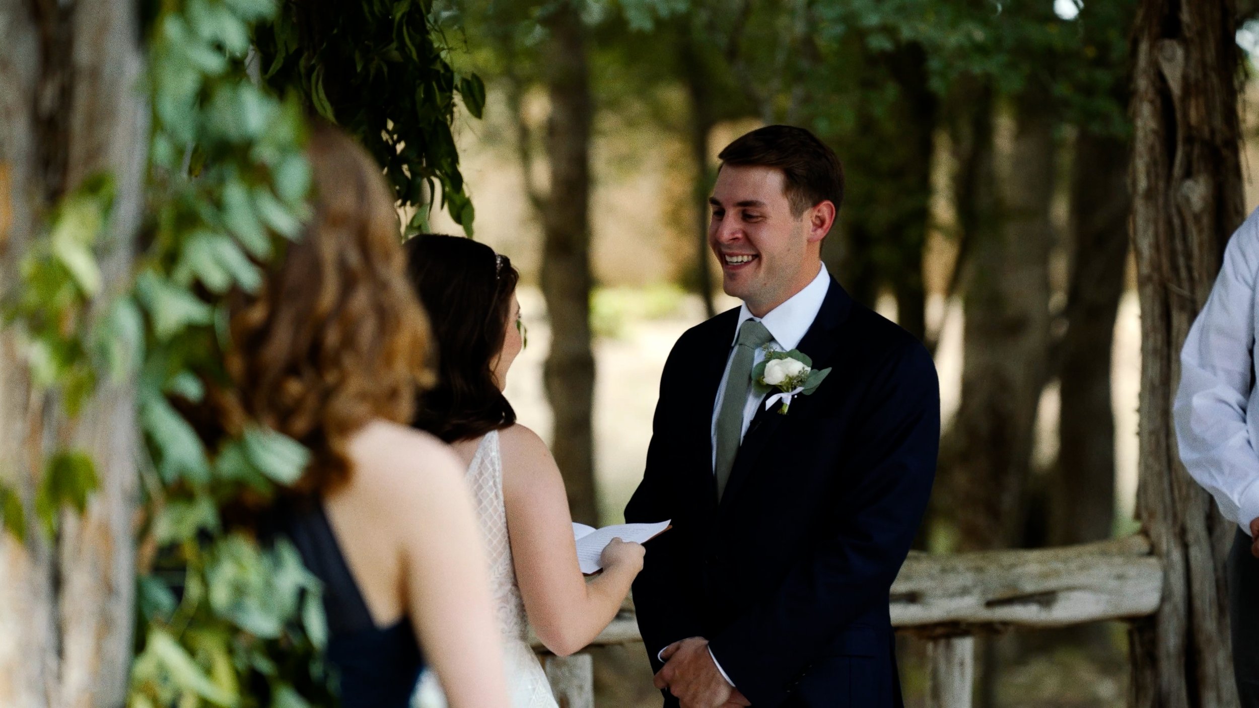 groom laughs at bride reading vows during wedding ceremony