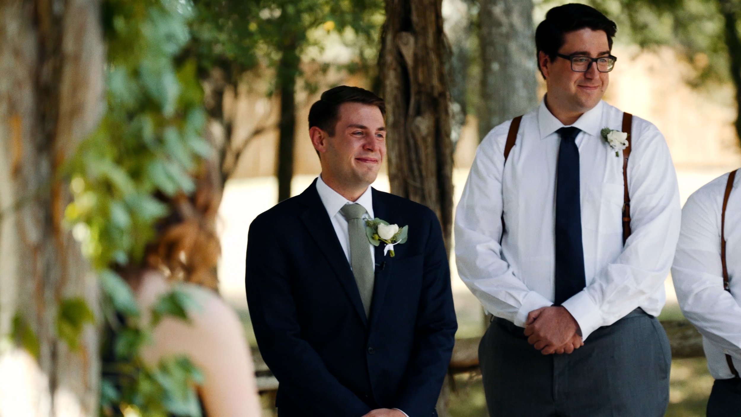 groom sees bride walking down aisle in wedding ceremony emotional smiling