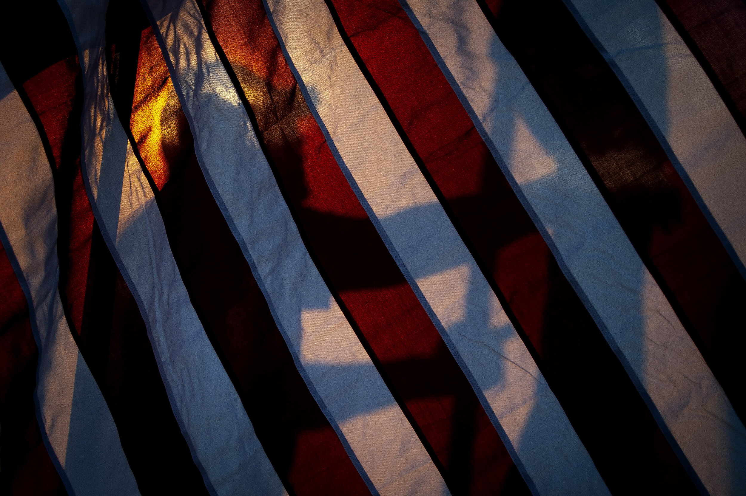  A helper is silhouetted through an American flag while assisting in assembling the Avenue of Flags for Patriot Day on Sept. 11 at Cape Girardeau County Park North in Cape Girardeau. 