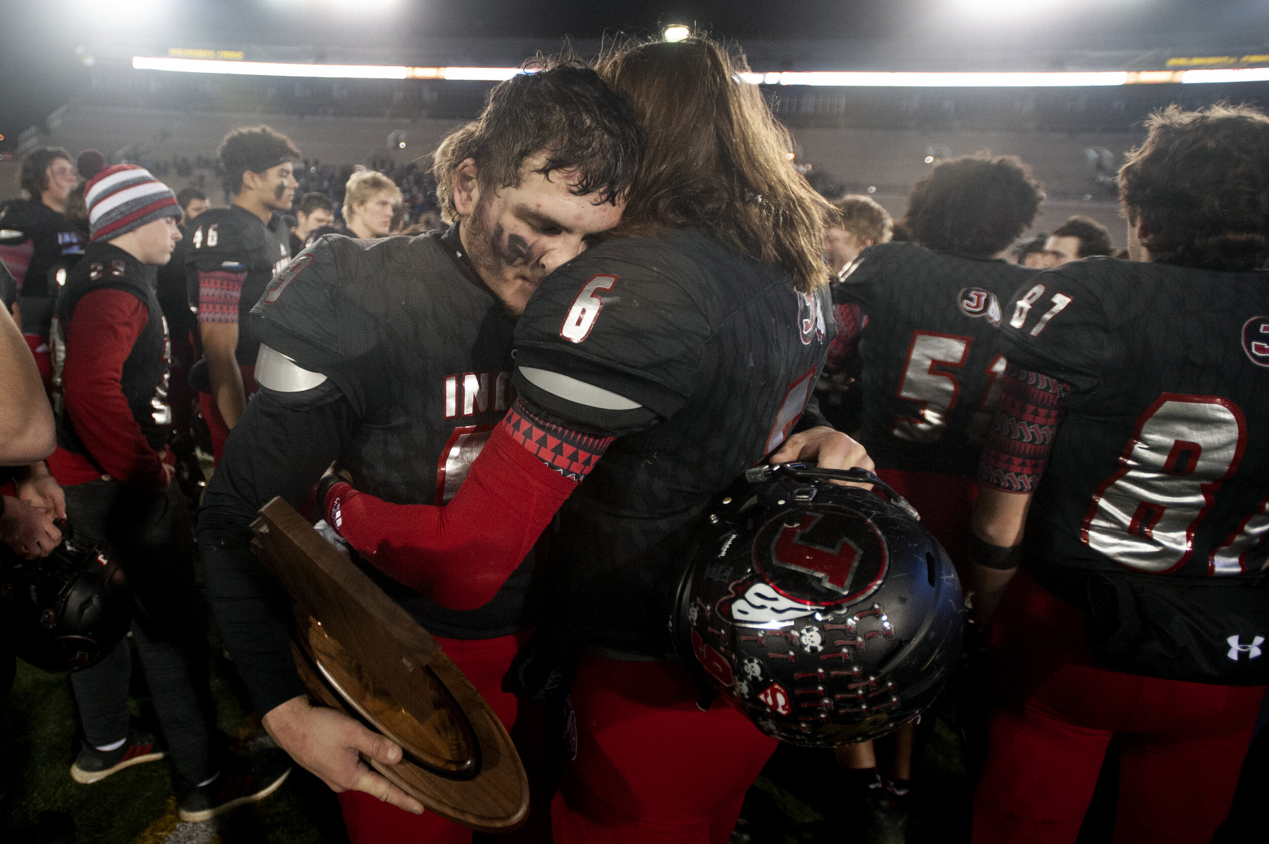  Jackson's Cael Welker (6) and Cole Amelunke (99), holding the Indians' second place trophy, hug following the team’s 27-21 overtime loss to Carthage in the MSHSAA Class 5 state championship Dec. 7 at Faurot Field in Columbia, Missouri.  