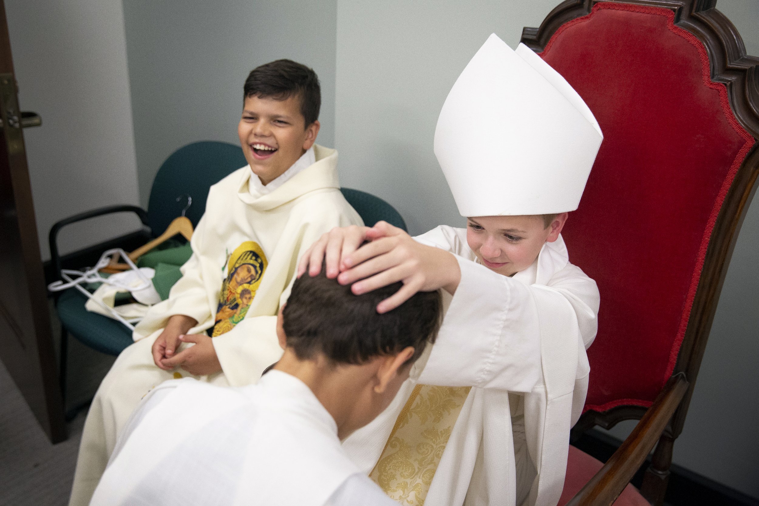  While learning about priest ordinations, Michael Lenzenhuber played role of bishop during the laying on of hands with John Paul Schmidt (head bowed) and Elijah Dwyer (left) during Kenrick-Glennon Days summer camp June 14 at Kenrick-Glennon Seminary 