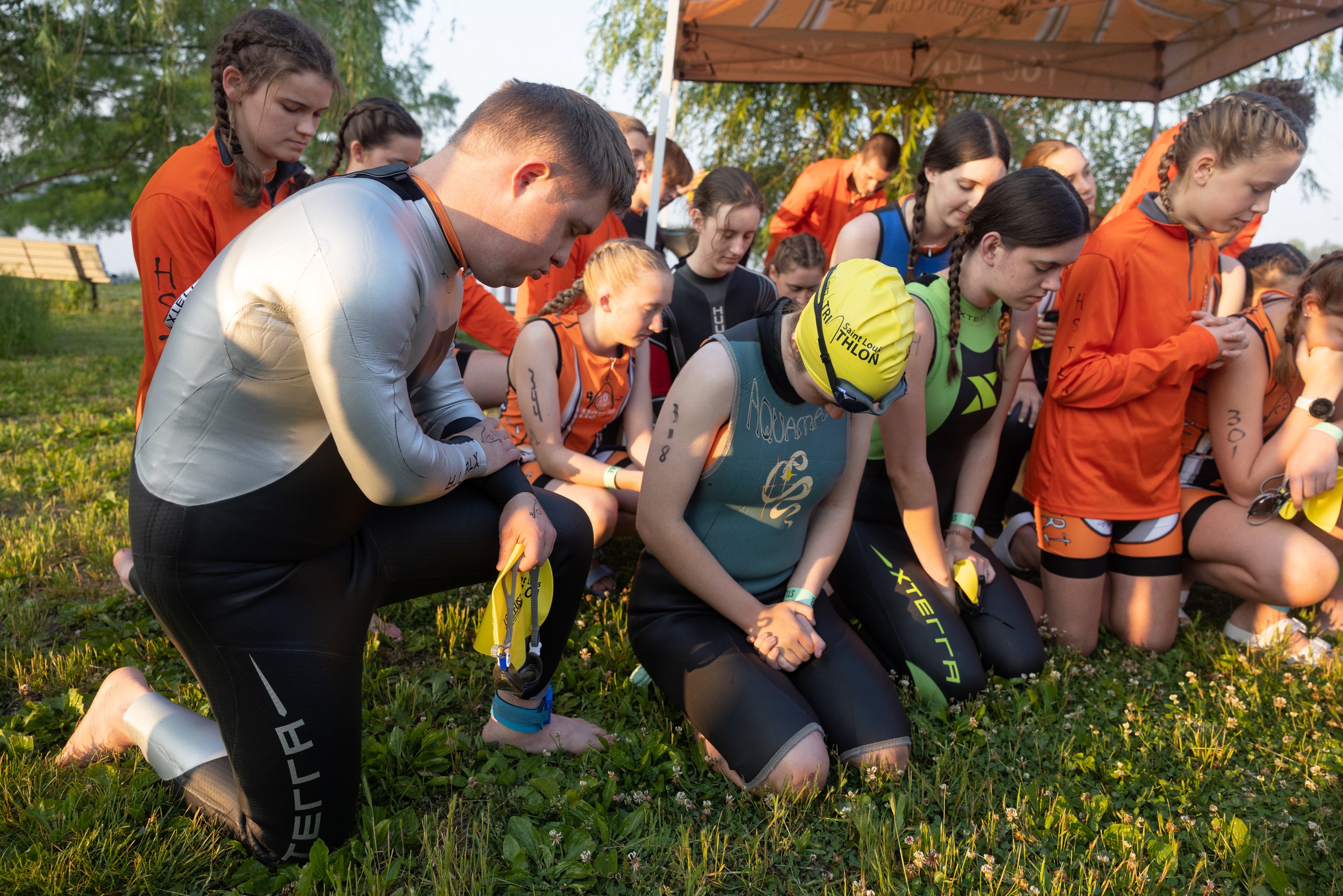  Gabriel knelt during a prayer with other members of the High School Triathlon Club before his second triathlon of the year May 21 at Creve Coeur Lake.  