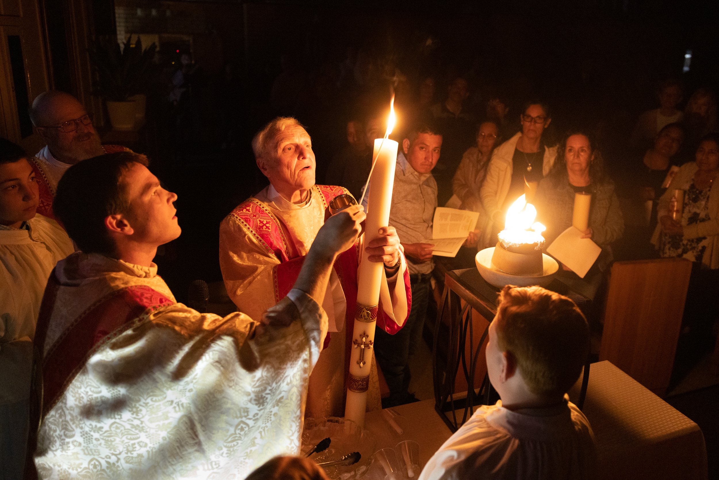  Father Tom Vordtriede lit a paschal candle held by Deacon Ray Burle at the start of the Easter Vigil on Saturday, April 8, 2023, at Holy Rosary Parish in Warrenton, Missouri. At the Mass, 24 people from the parish were received into the Catholic Chu