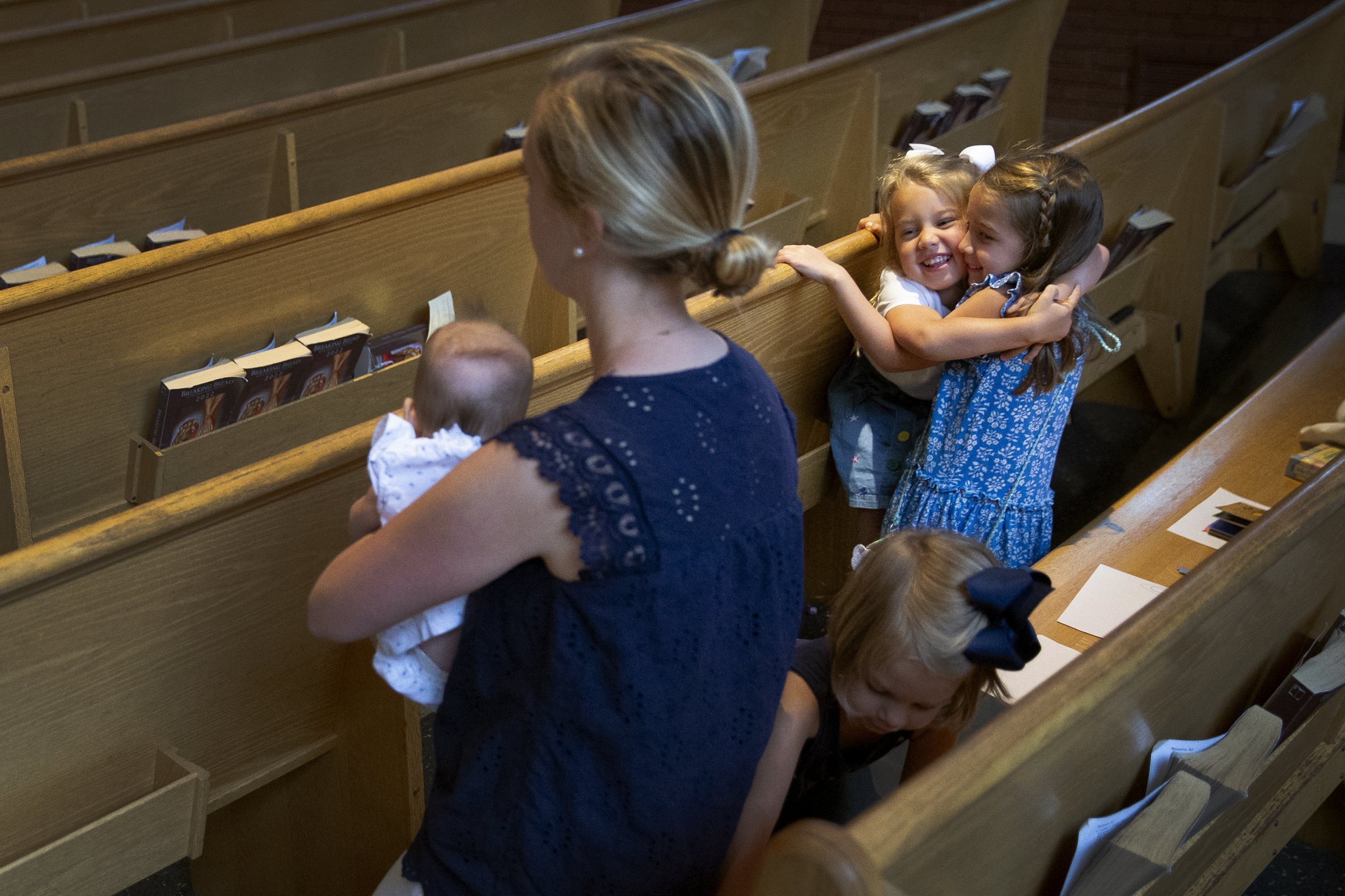  Eliza Rosa, 4, (left in hug) and Maria Rosa, 6, embraced during Mass next to their mother, Caroline Rosa, and siblings Josephine Rosa, 3, and Frances Rosa, 5 months, on June 10 at St. Peter Church in Kirkwood, Missouri. The Rosas have been parishion