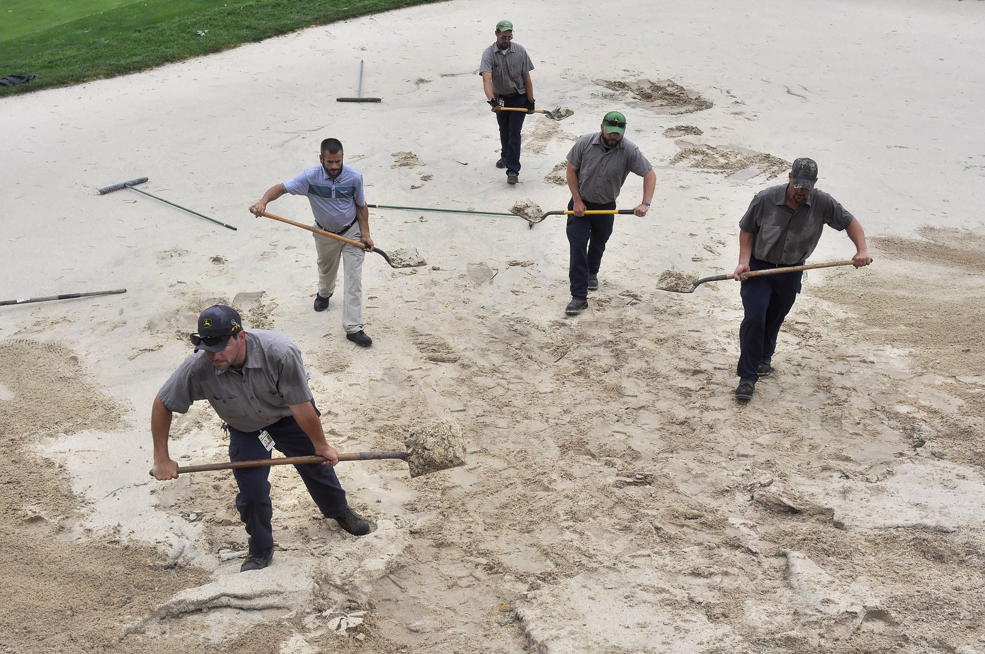  Grounds crew members work to clean up a sand trap on the 2nd hole of TPC Deere Run during a delay in play of the John Deere Classic on the morning of Friday, Aug. 12, 2016, in Silivs. Play is currently schedule to resume at noon. 