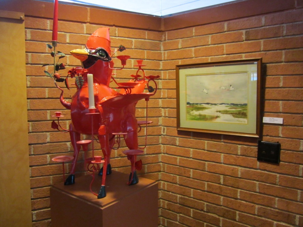 A cardinal happily holding candles on display at Prairie School with a painting by Bill’s mom.