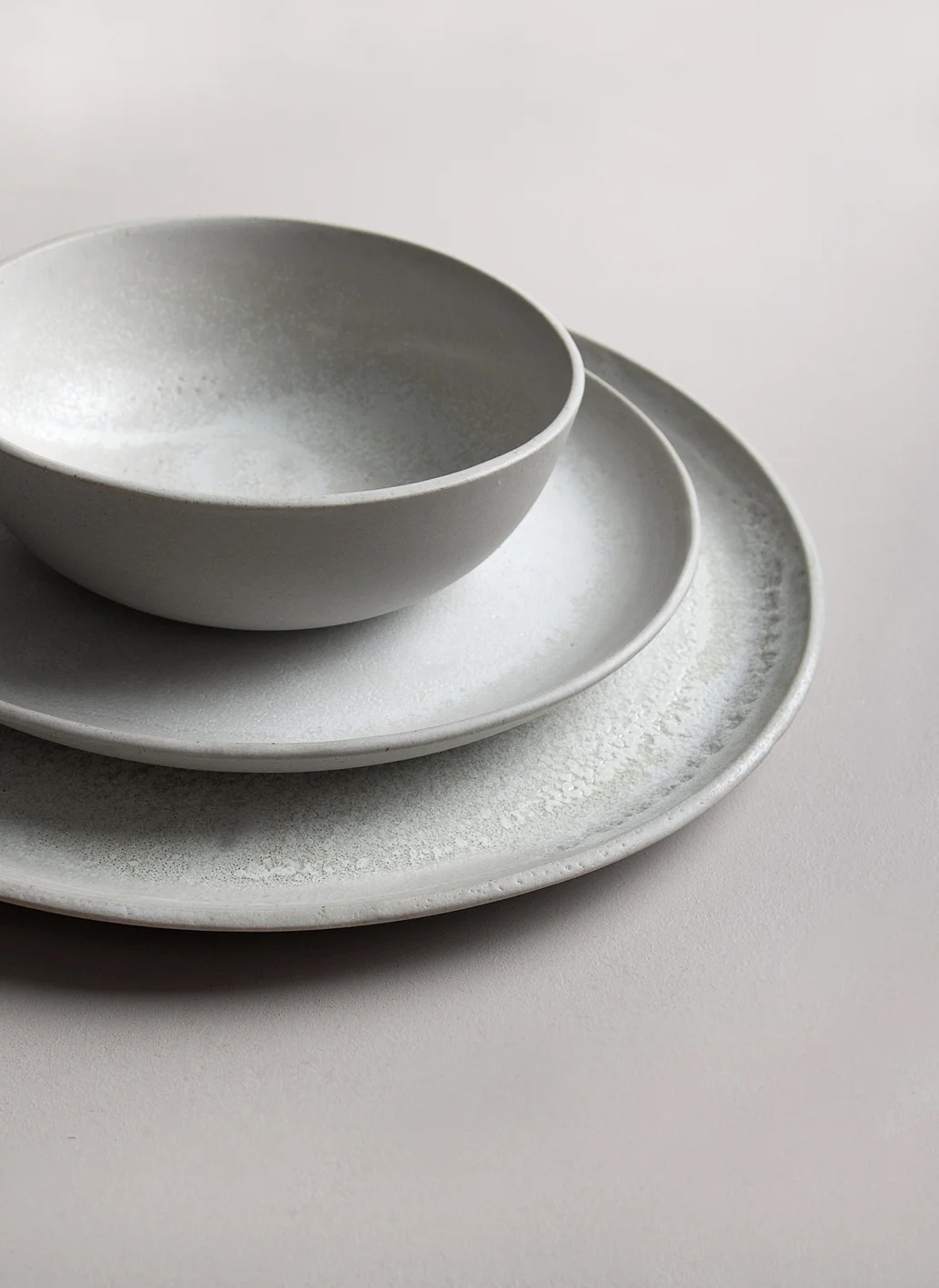 Grey plates and bowls with lively glazing on top.