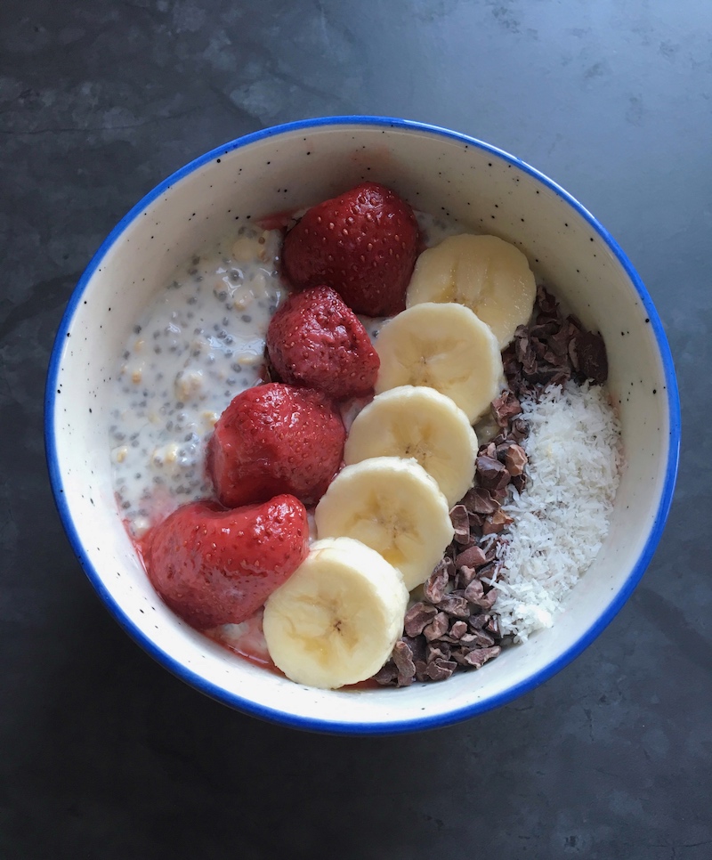 Overnight oats topped with strawberries, banana slices, cacao nibs, and coconut flakes to fuel a busy day