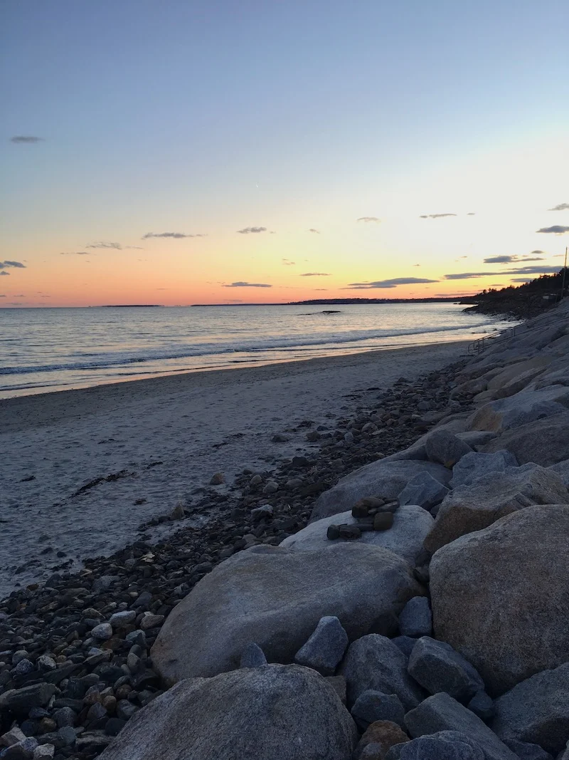Walks along the beach while the sun goes down