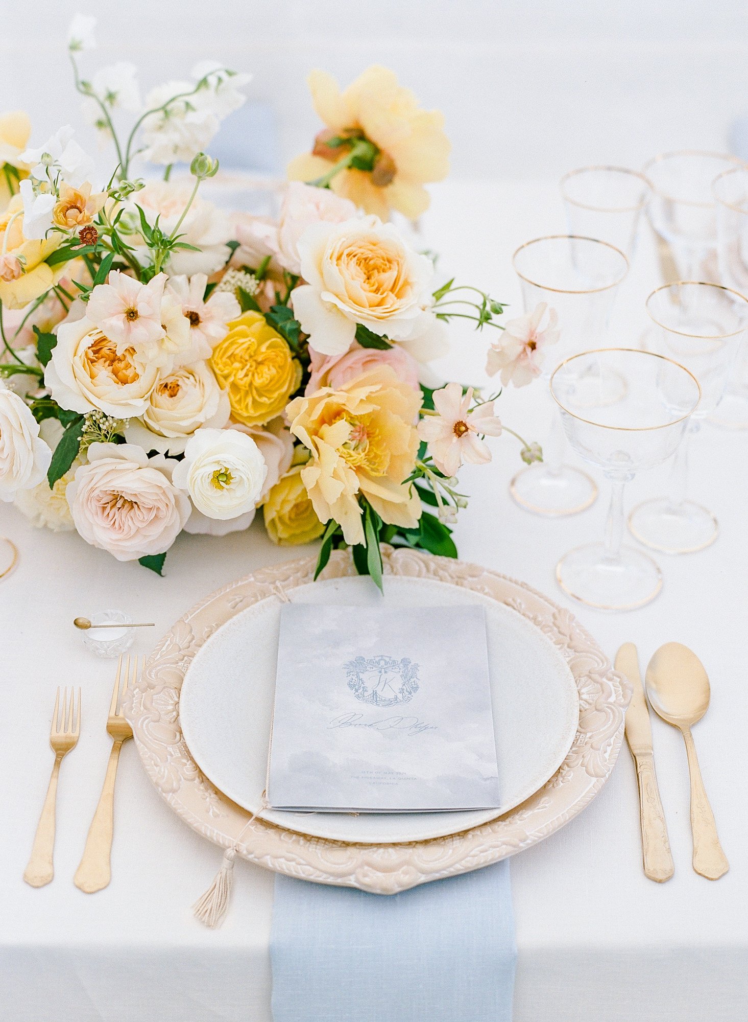 Table setting at a wedding by Oregon wedding planners Bridal Bliss, with yellow and ivory flowers laying on the table