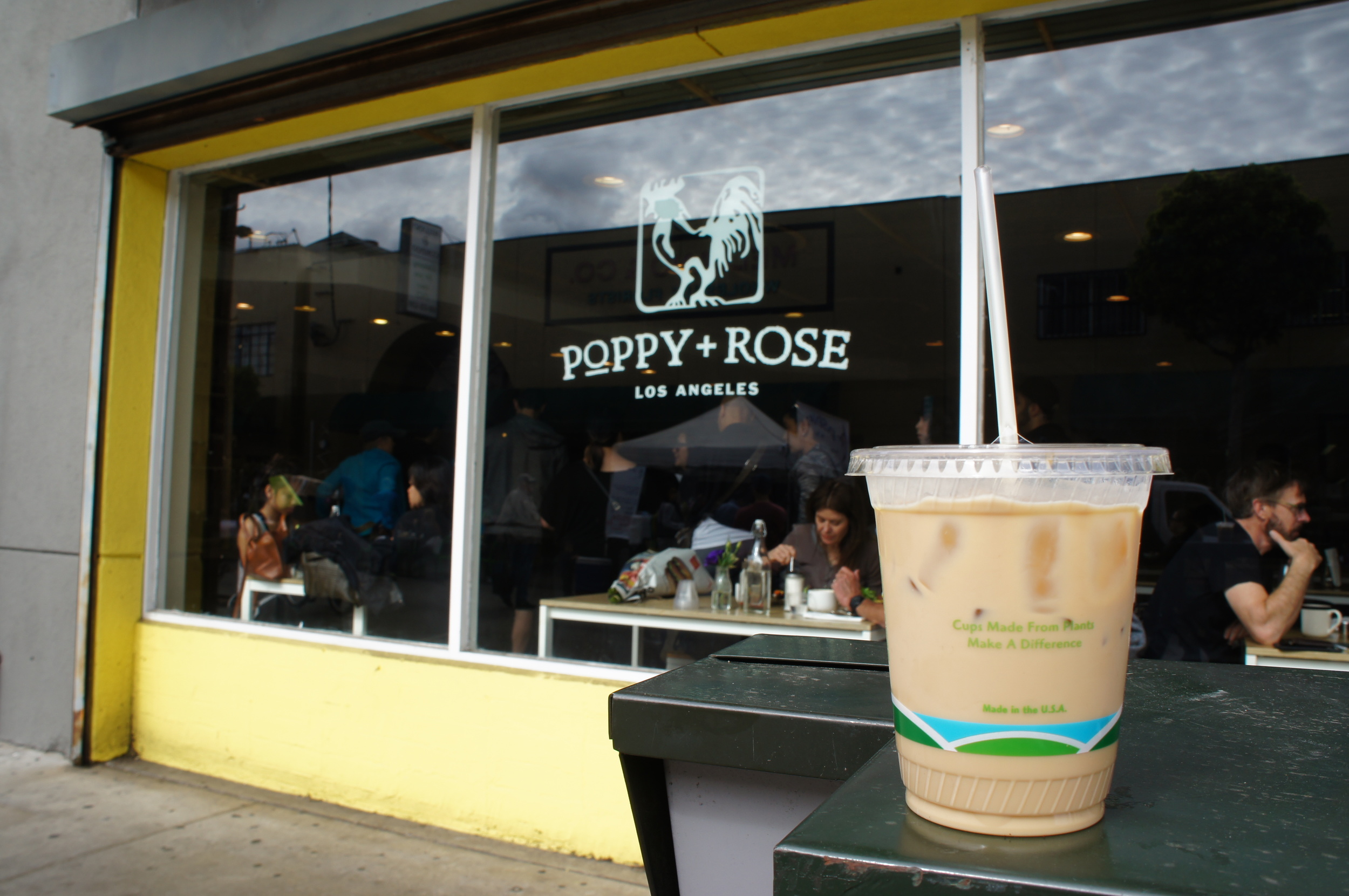 Iced coffee in takeaway cup in front of Poppy and Rose coffee shop in Los Angeles