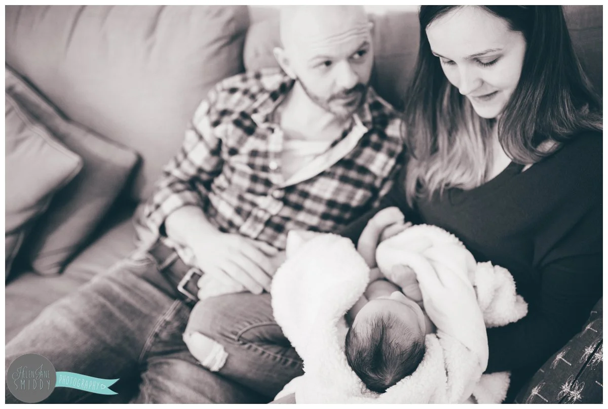 Husband looks adoringly at his wife and new baby daughter.