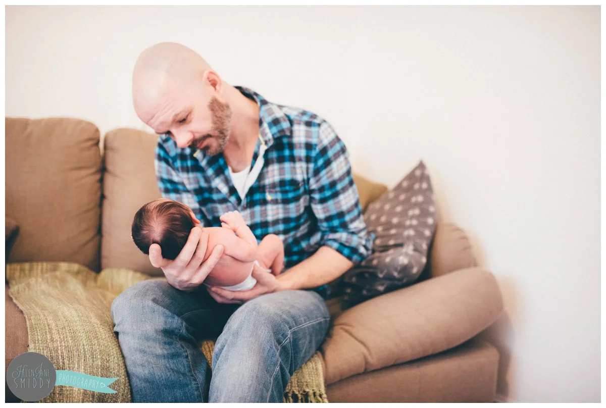 New Dad looks at his beautiful week old daughter whilst settling her to sleep.