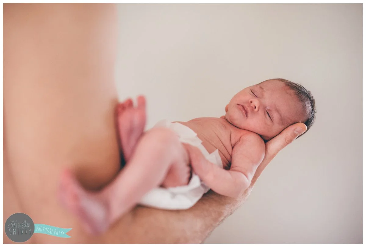 Topless dad holds his baby girl whilst she sleeps during their family photoshoot in Frodsham, Cheshire.