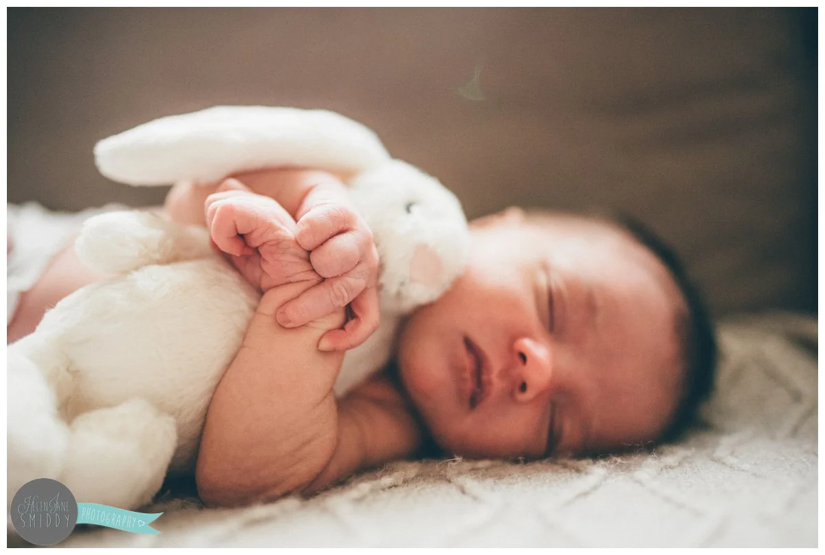 Close-up of baby cuddling her fluffy bunny rabbit whilst she sleeps.
