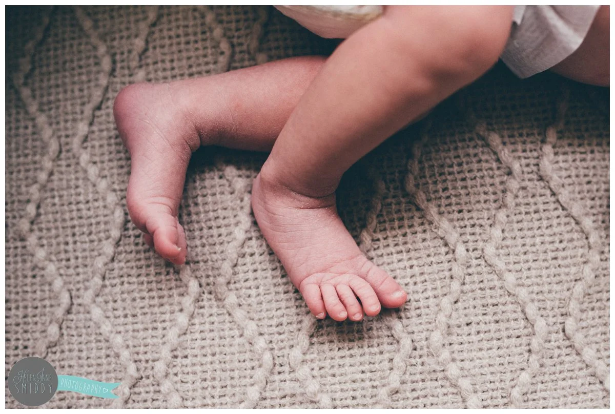 Newborn baby's wrinkly feet and cute toes on the cable-knit blanket.