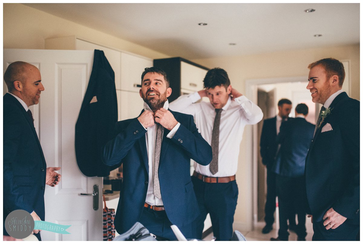 One of the groomsmen arrived late so laughs as he rushes to get ready.