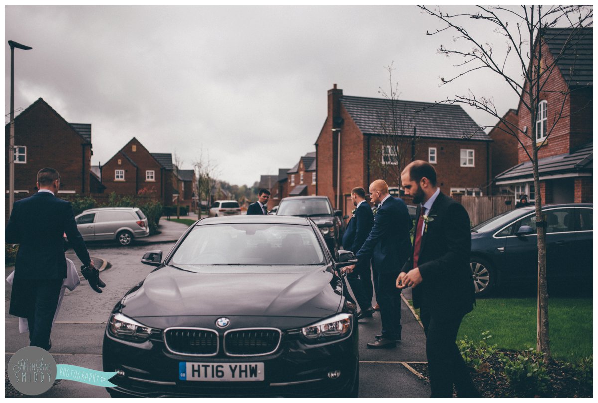 The groom and all the groomsmen begin to get in the car to go to church.