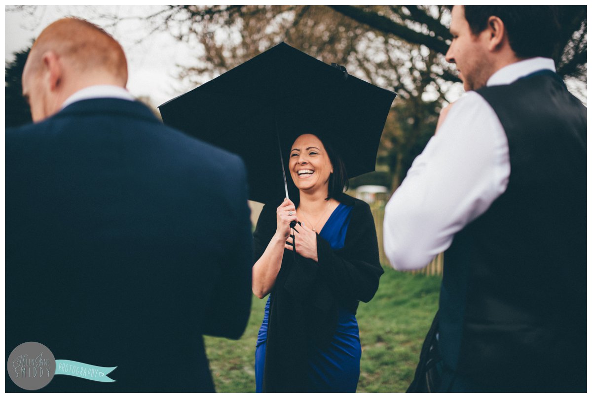 Pretty wedding guest chats to the groom under her umbrella before the wedding ceremony.