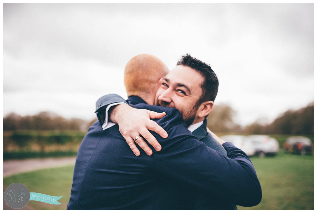 Wedding guest hugs the groom when he arrives at Toft church.