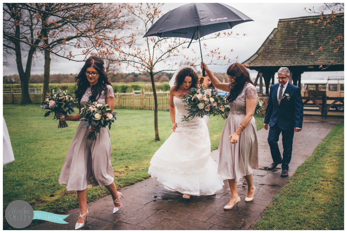 The bridesmaid helps the bride as it rains on the morning of the wedding.