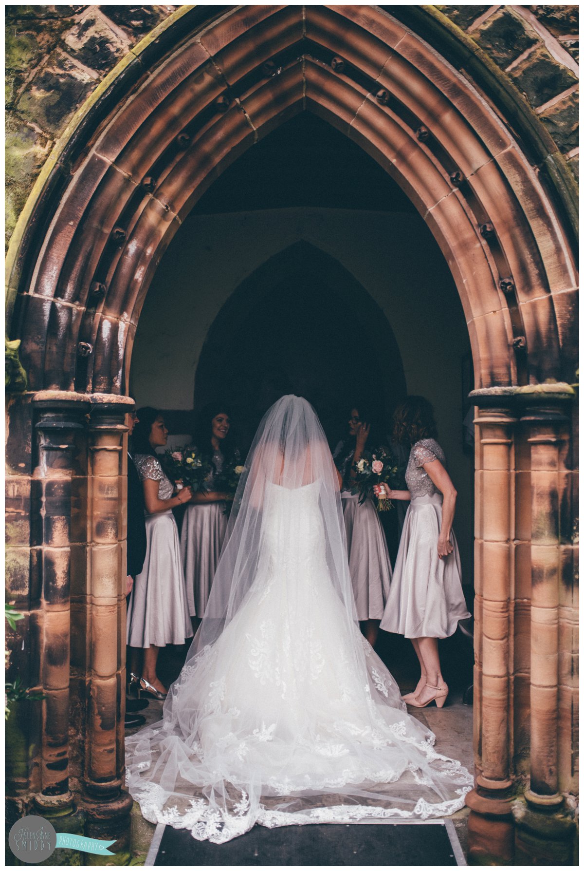 The back of the bride's beautiful Maggie Sottero gown as she stands in the archway at Toft Church in Knutsford.