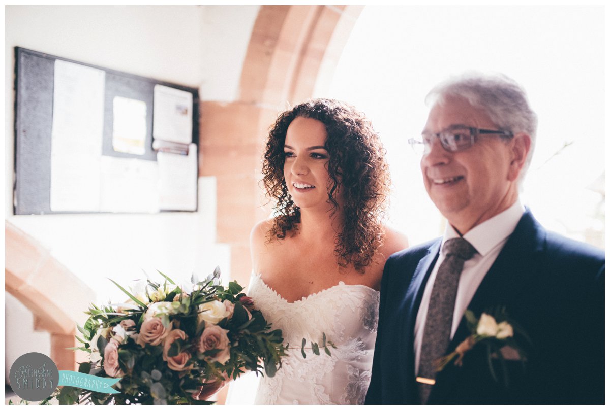 The bride smiles with her father before they walk down the aisle together.