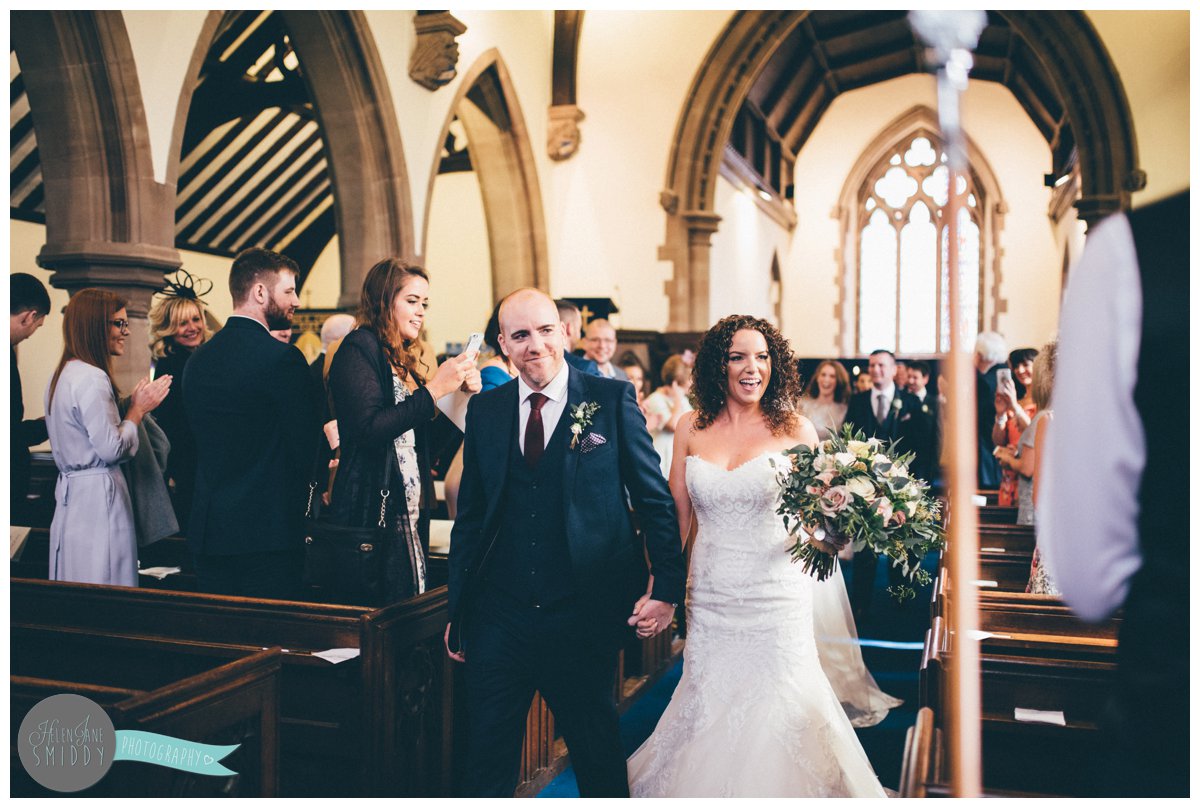 New husband and wife are so happy as they grin their way down the aisle.