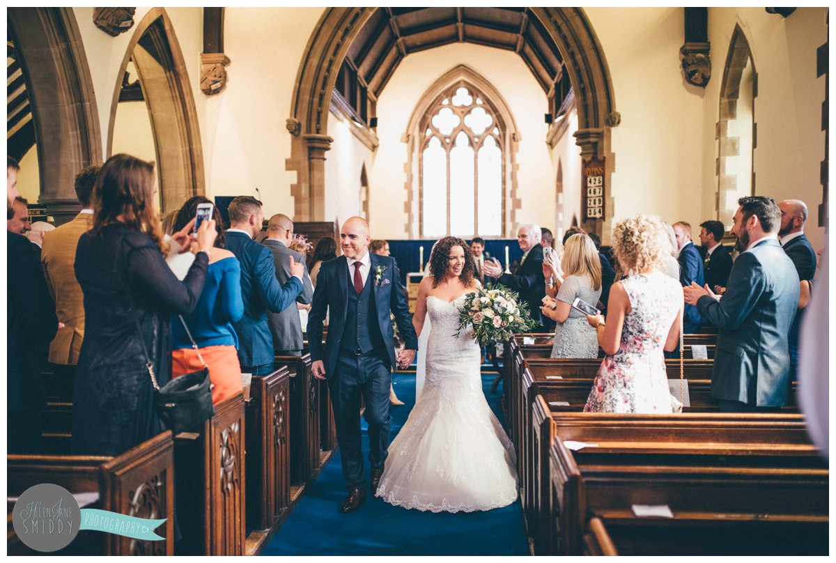 Lyssa and Dom walk back down the aisle together as husband and wife, smiling and holding hands.