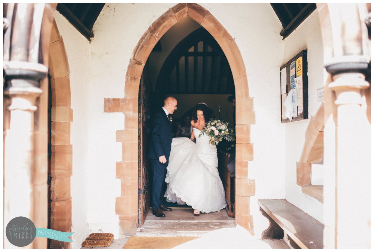 Bride and Groom leave Toft Church together whilst he helps her with her Maggie Sottero dress.