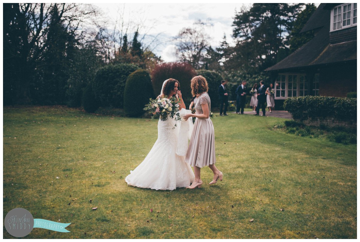 The beautiful bride and her best friend share a laugh as they walk across the lawn at Mere Court Hotel in Knutsford.