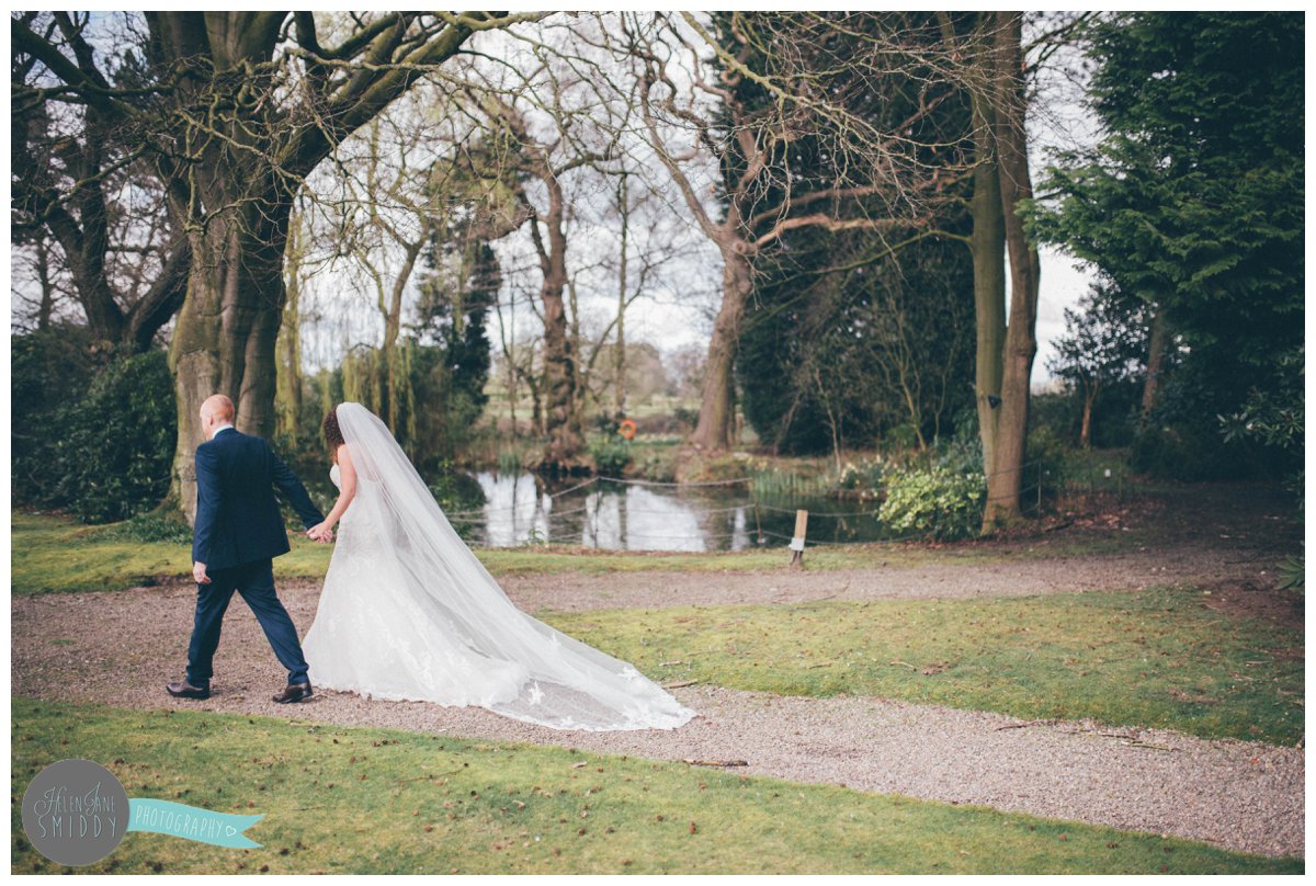 Lyssa's beautiful veil hangs perfectly as the bride and groom walk hand-in-hand outside at Mere Court Hotel.