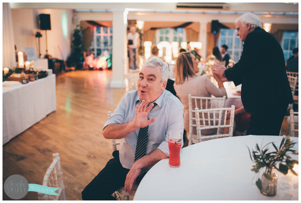 A friendly wedding guest jokes with the wedding photographer about not wanting his photograph taken.