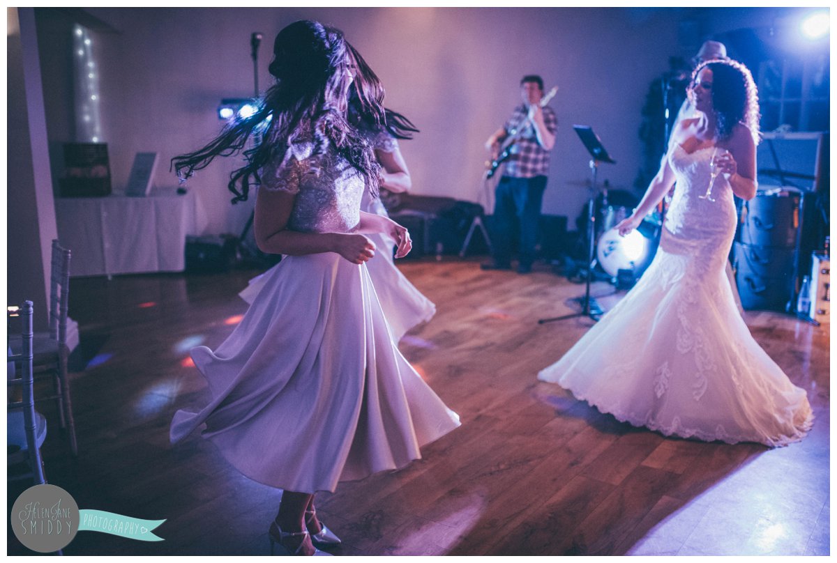 The bride dances with the bridesmaids and they all twirl around in their beautiful dresses.