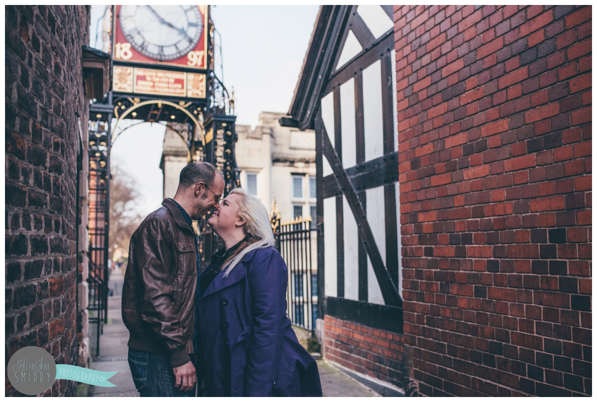 Young couple kiss on the bridge of the Eastgate Clock in Chester, Cheshire.