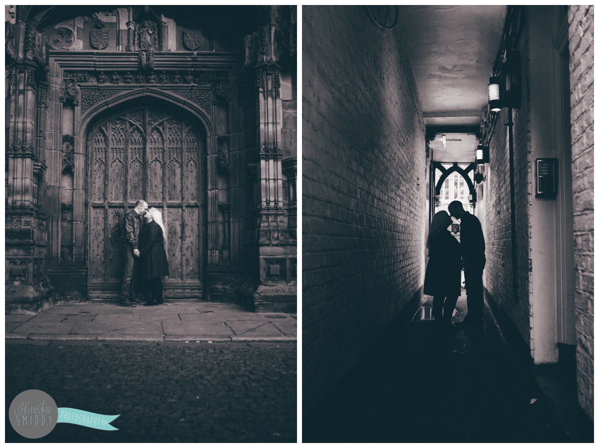 Couple face each other and hold hands, whilst stood in front of the beautiful big brown door of Chester Cathedral during their engagement shoot.
