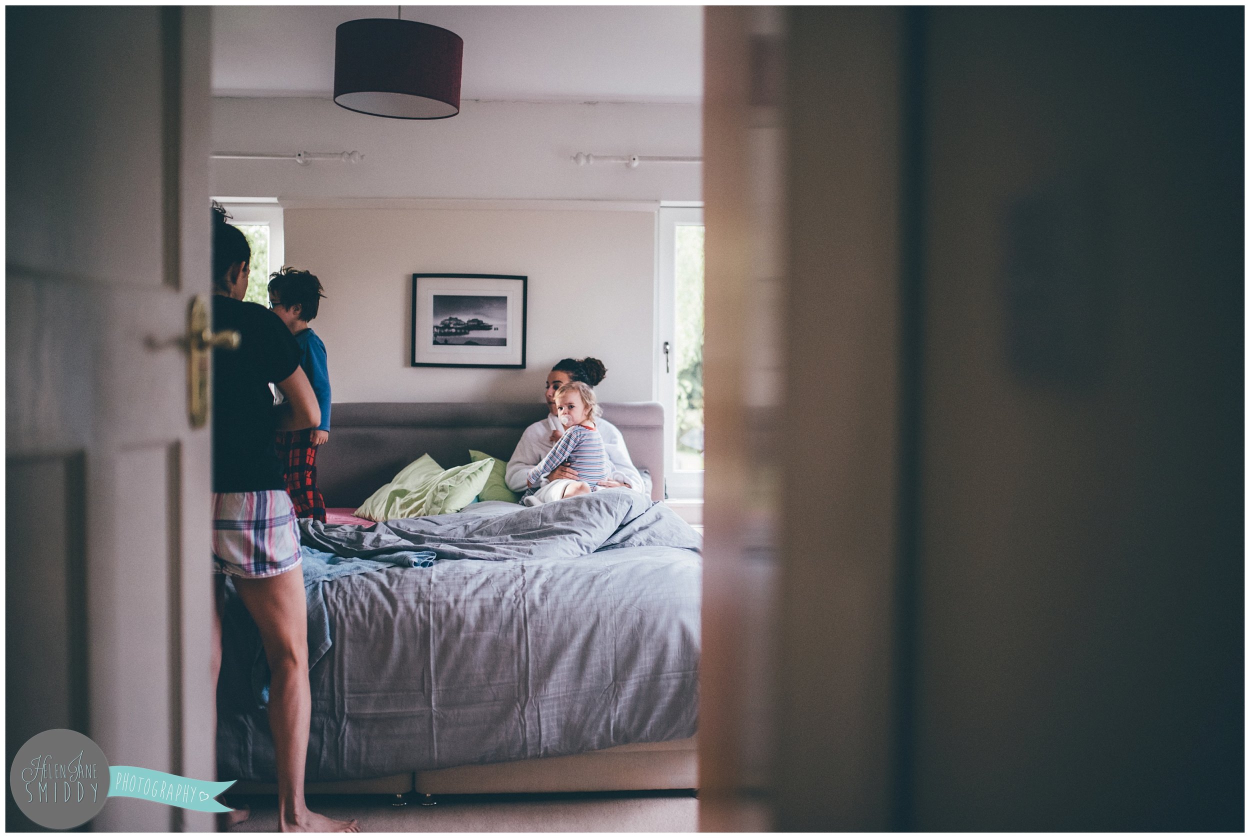 The family sit on the bed, waking up before getting ready for their day.