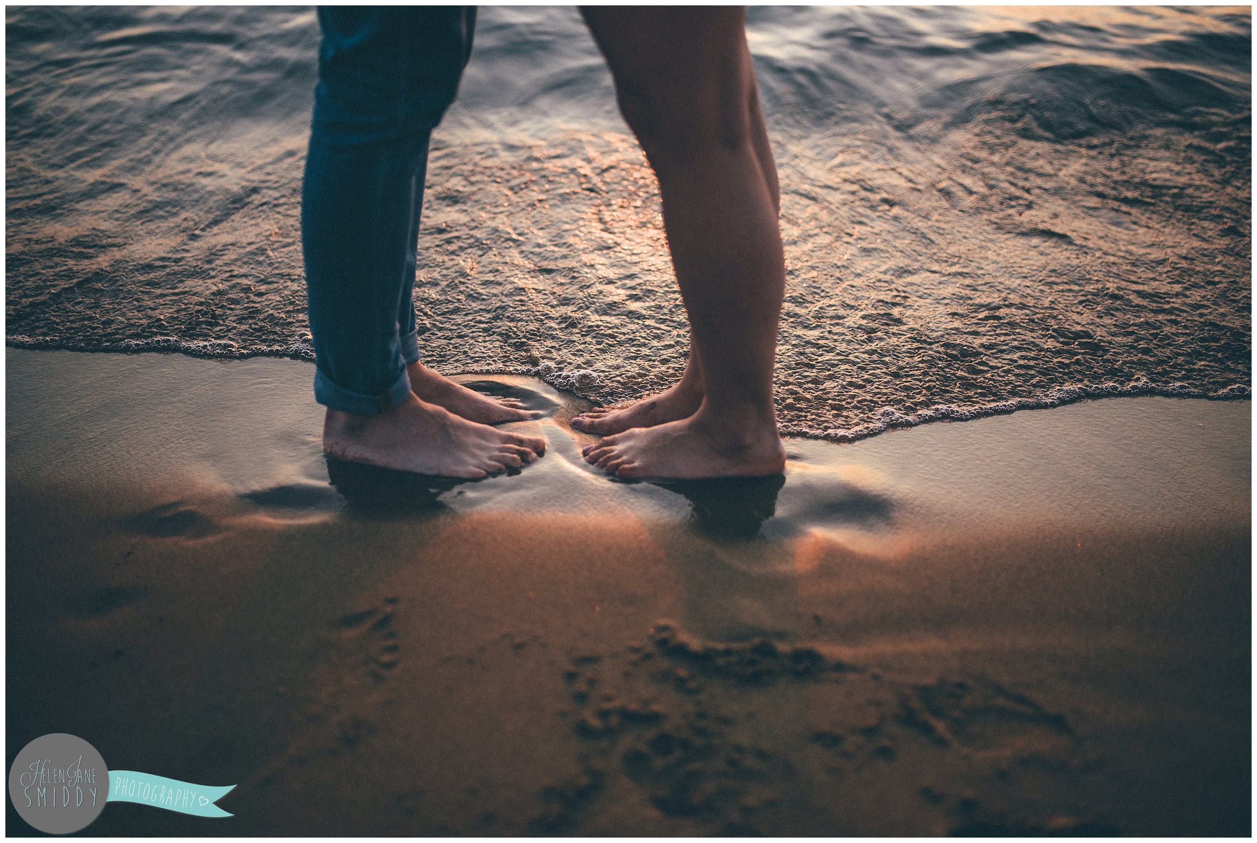 Dom and Sabrina's feet in the sand on the beach at sunset.
