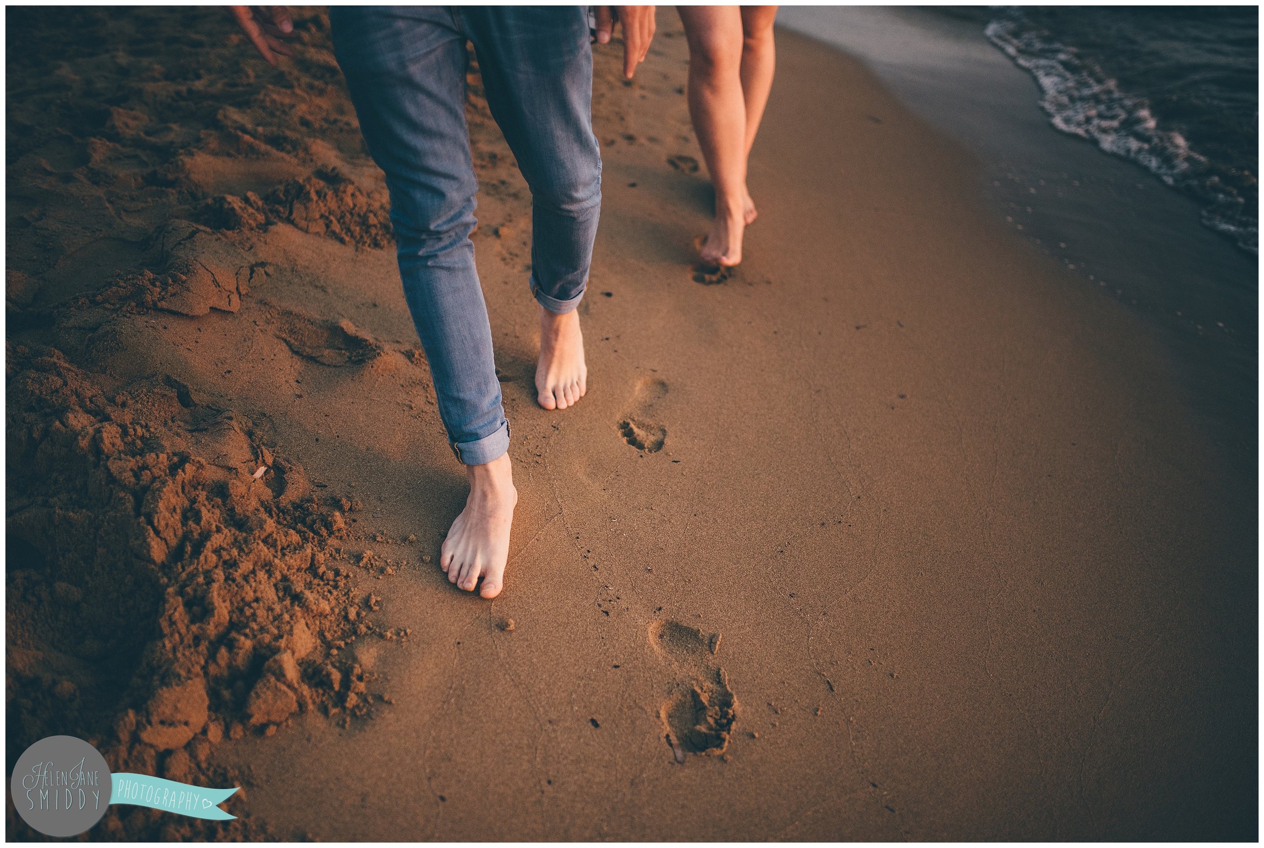 Sabrina and Dom make footprints in the sand during their engagement shoot in Italy.
