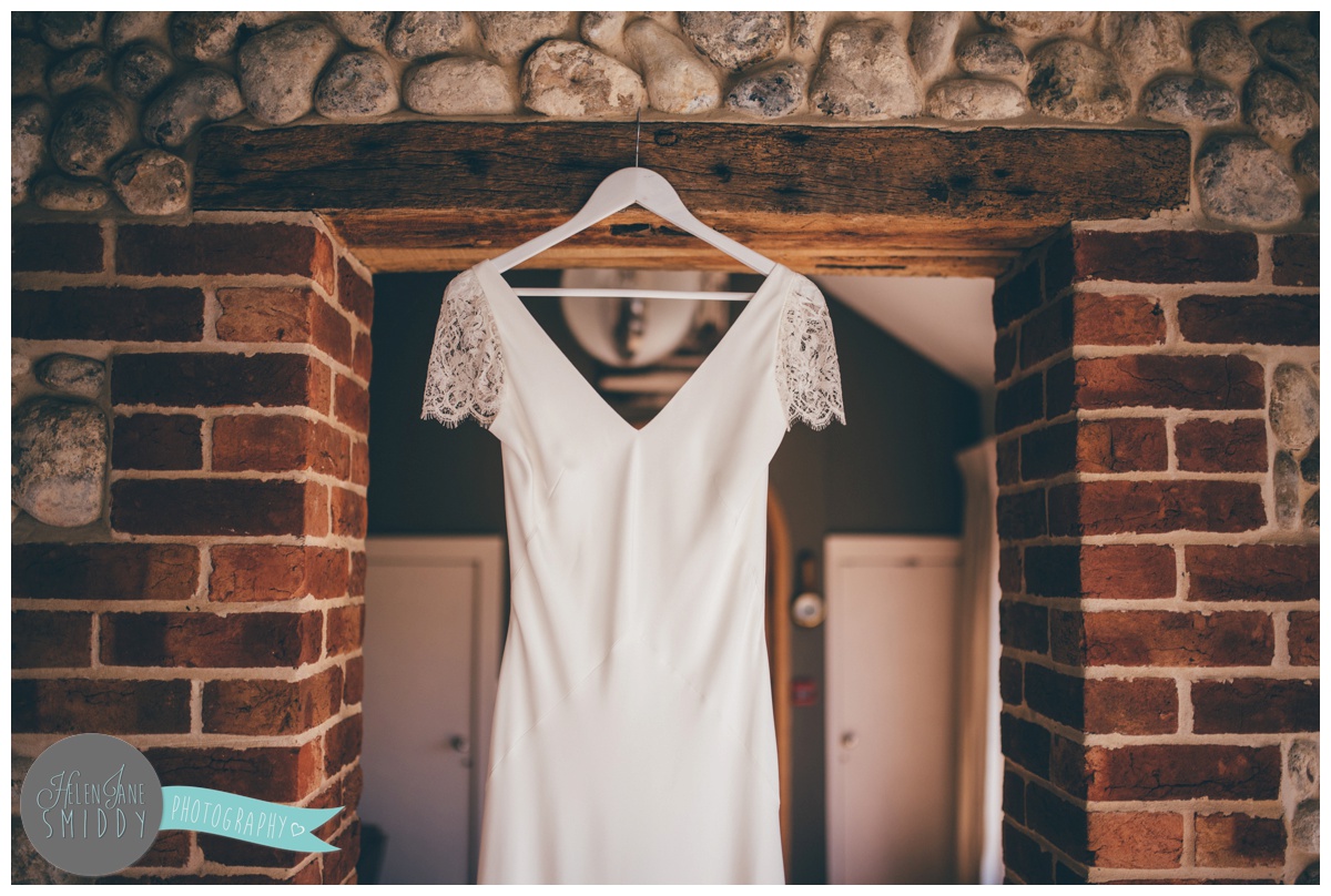 Sarah's beautiful slim-fitted wedding gown hung up at Barn Drift in Norfolk.