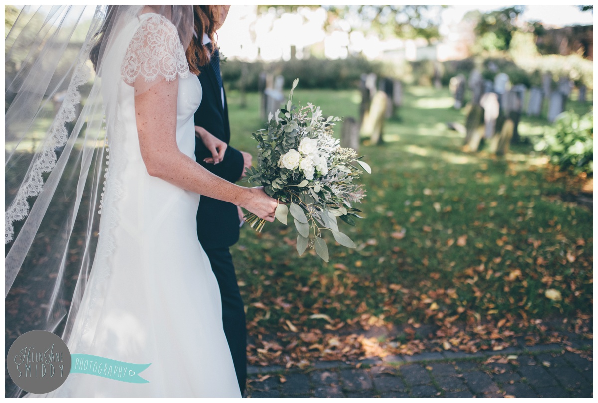 Father of the Bride leads his daughter towards the church in the sun.