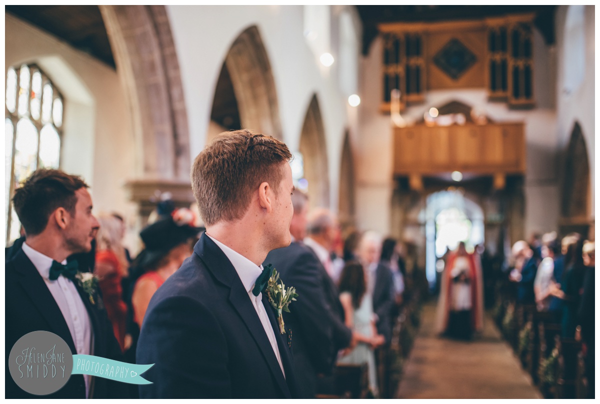 Groom, Joe, looks at his bride walking down the aisle.