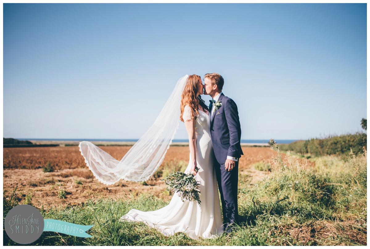 Newlyweds share a kiss at their stunning Norfolk venue on a sunny September day.