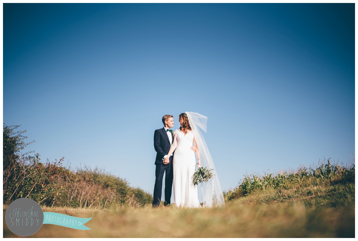 Couple kiss in front of beautiful blue skies in Norfolk.