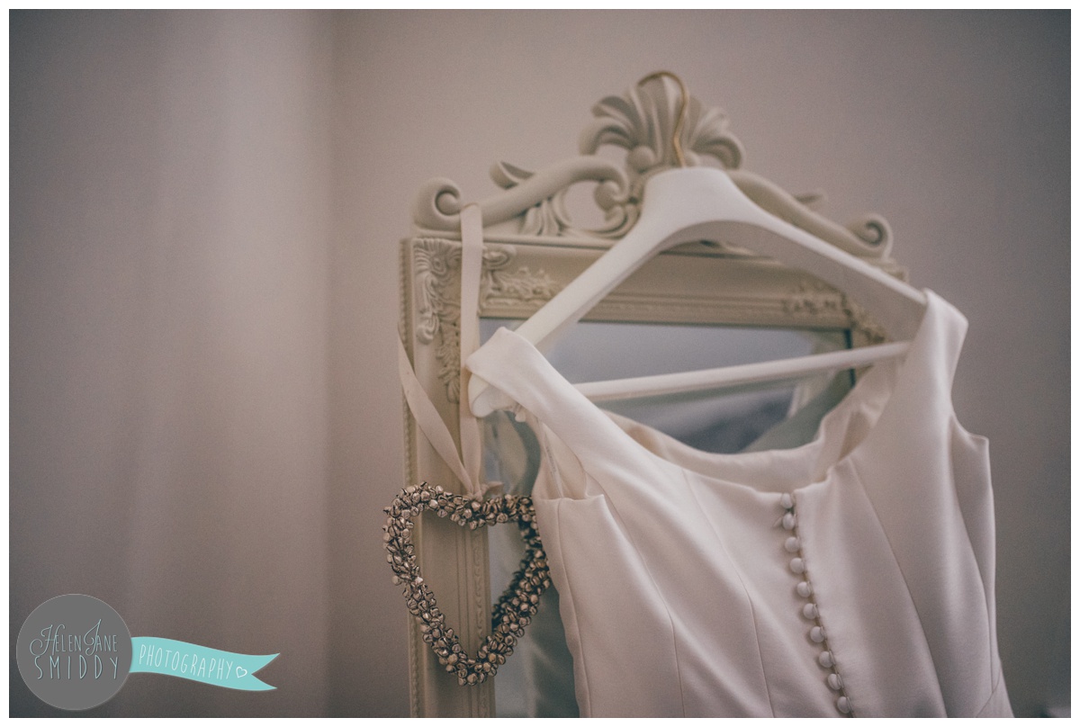 The bride's wedding gown hung up, showing the beautiful button up back.