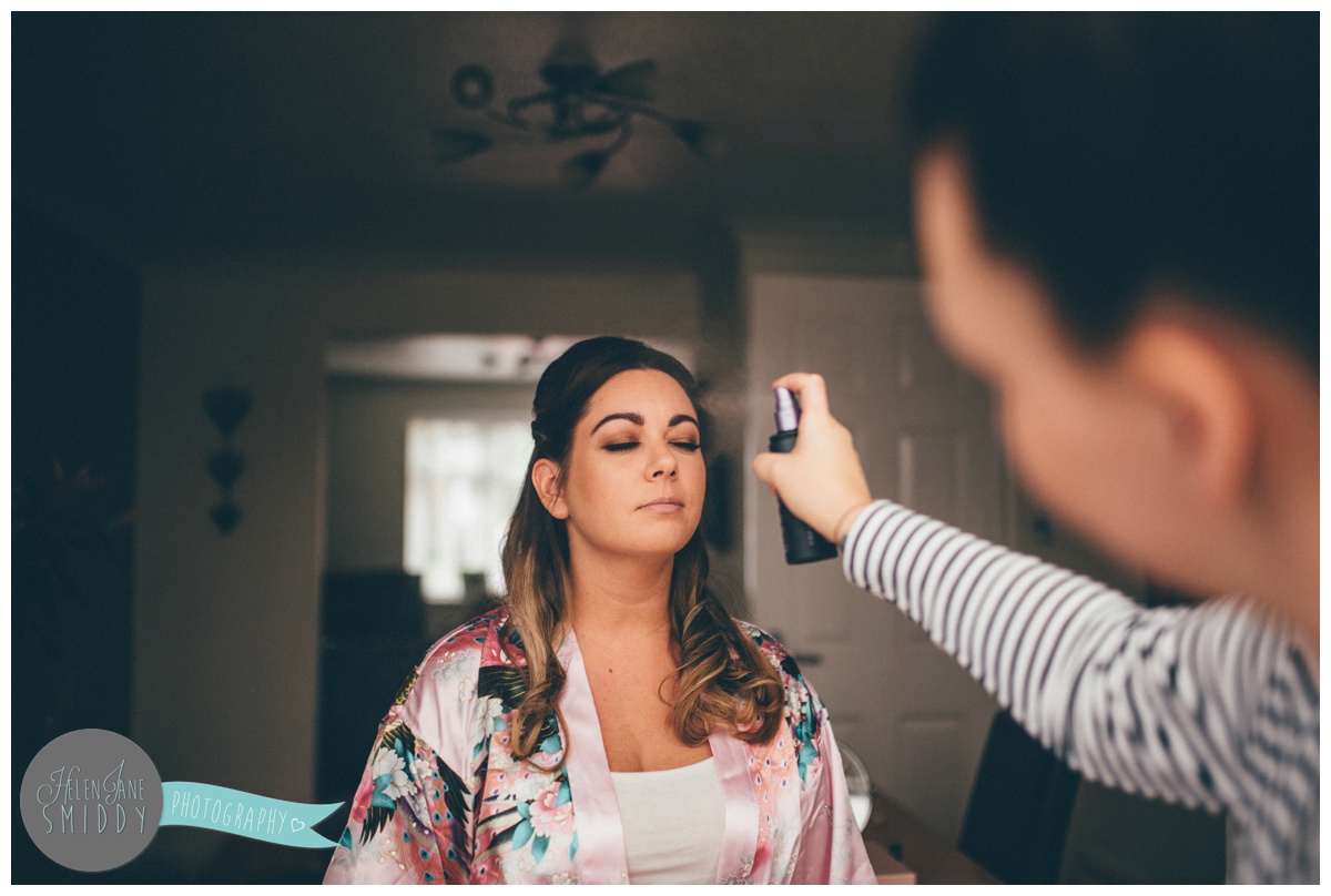 The Cheshire make-up artist sprays fixing spray on the bridesmaids face.