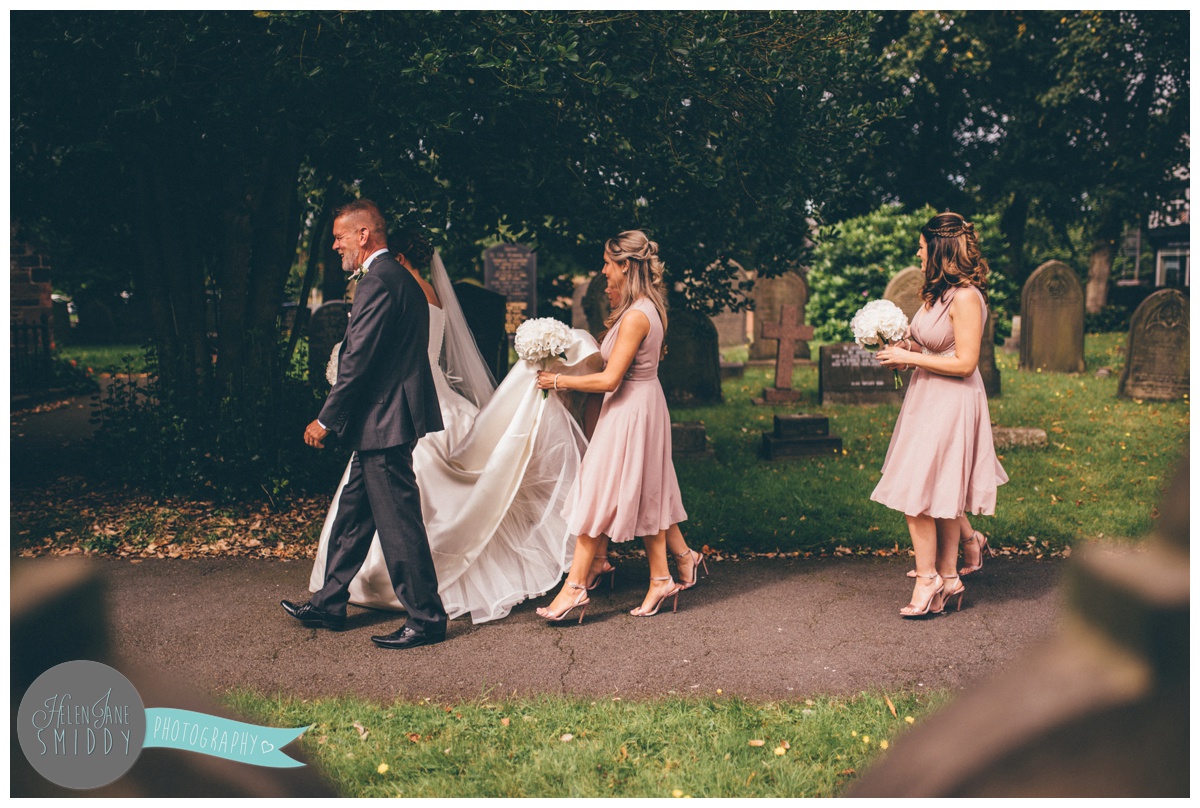Father of the bride leads his daughter and the bridal party into church.