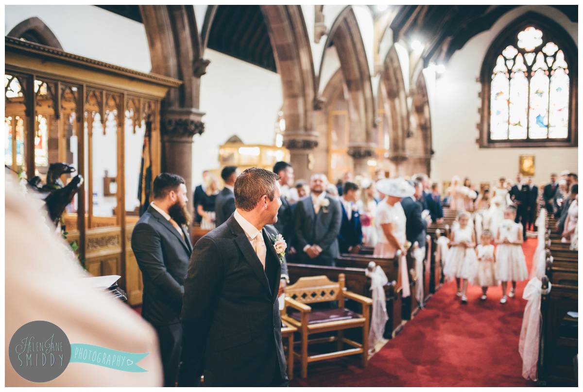 The bridal party walk down the aisle towards the groom.